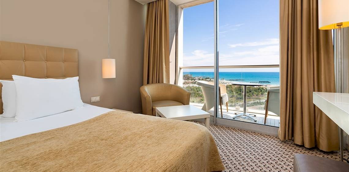 Hotelzimmer mit Meerblick im Crystal Centro Resort mit Bett, Sessel, Tisch und Panoramafenster.