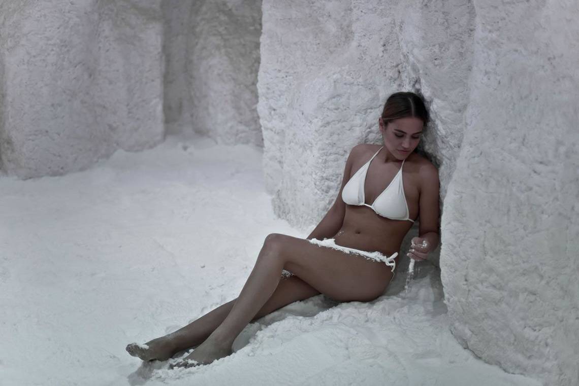 Frau im weißen Bikini liegt in einer Schneehöhle im Delphin Imperial Hotel.