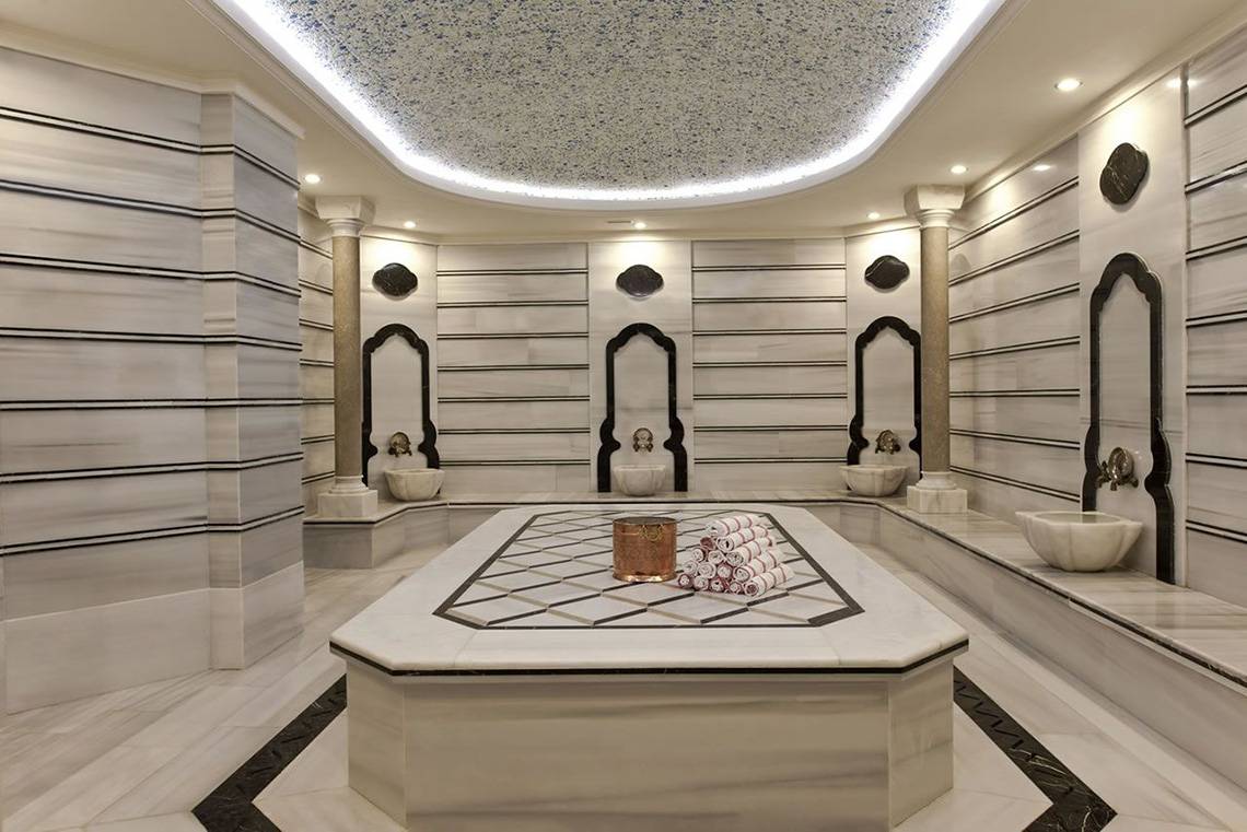 Innenansicht der Sauna im Delphin Imperial Hotel mit weißen Marmorwänden und zentralen Tisch.
