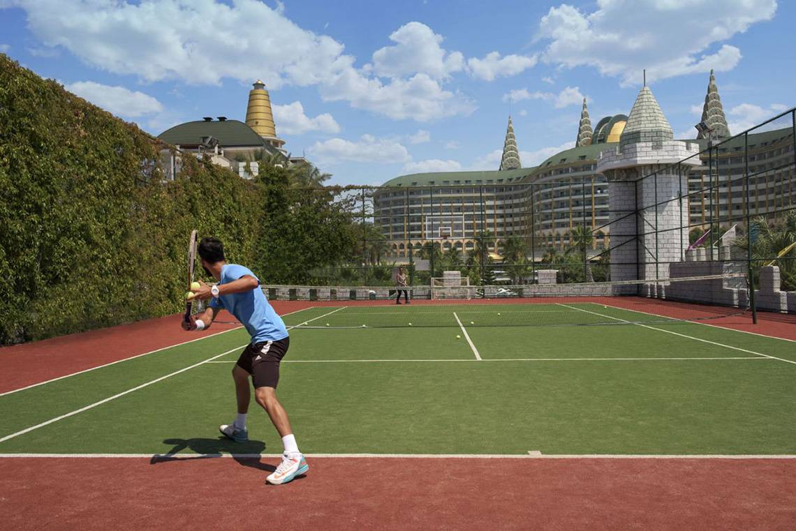 Tennisplatz vor dem Delphin Imperial Hotel mit einem Spieler in Blau.