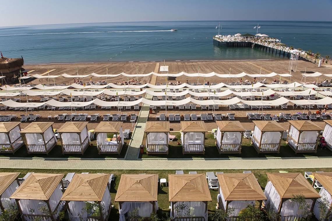Luftaufnahme des Delphin Imperial Hotels, Strand mit vielen weißen Sonnenzelten.