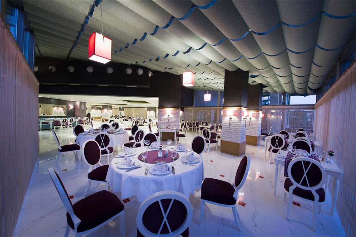 Restaurant im Limak Lara De Luxe Hotel & Resort mit gedeckten Tischen und Stühlen.