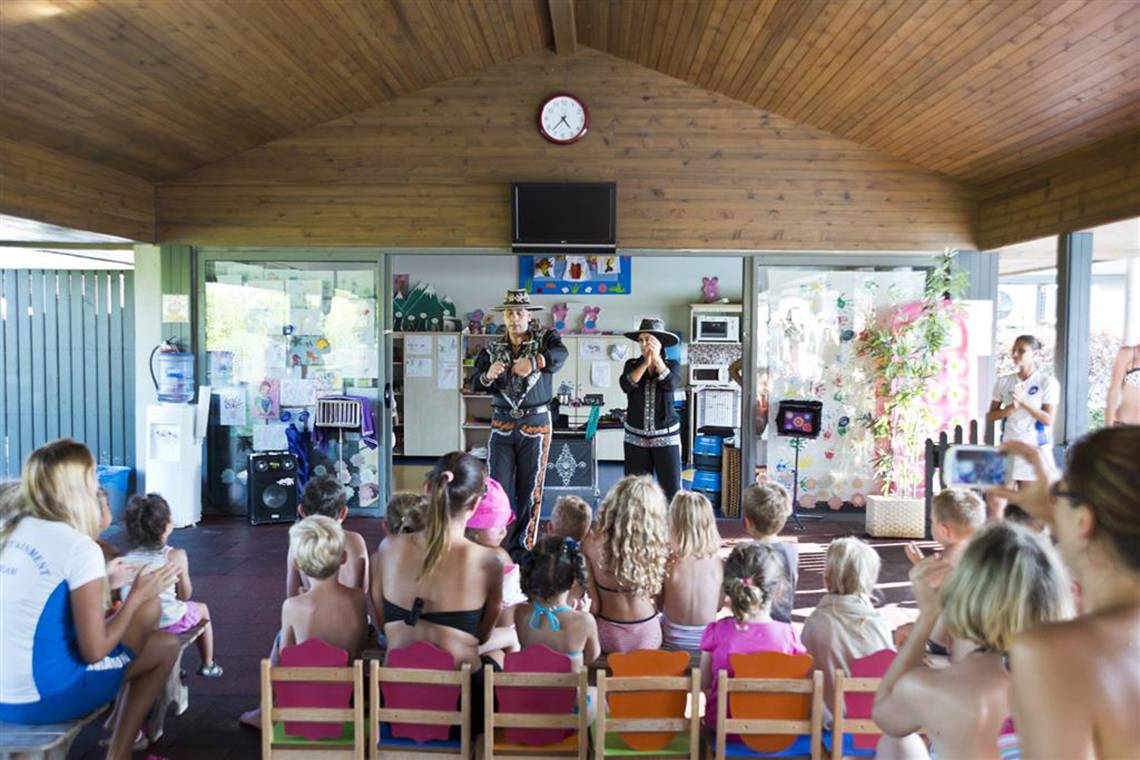 Zwei Erwachsene führen eine Show für Kinder im Hotel vor, während die Kinder und einige Erwachsene zusehen.