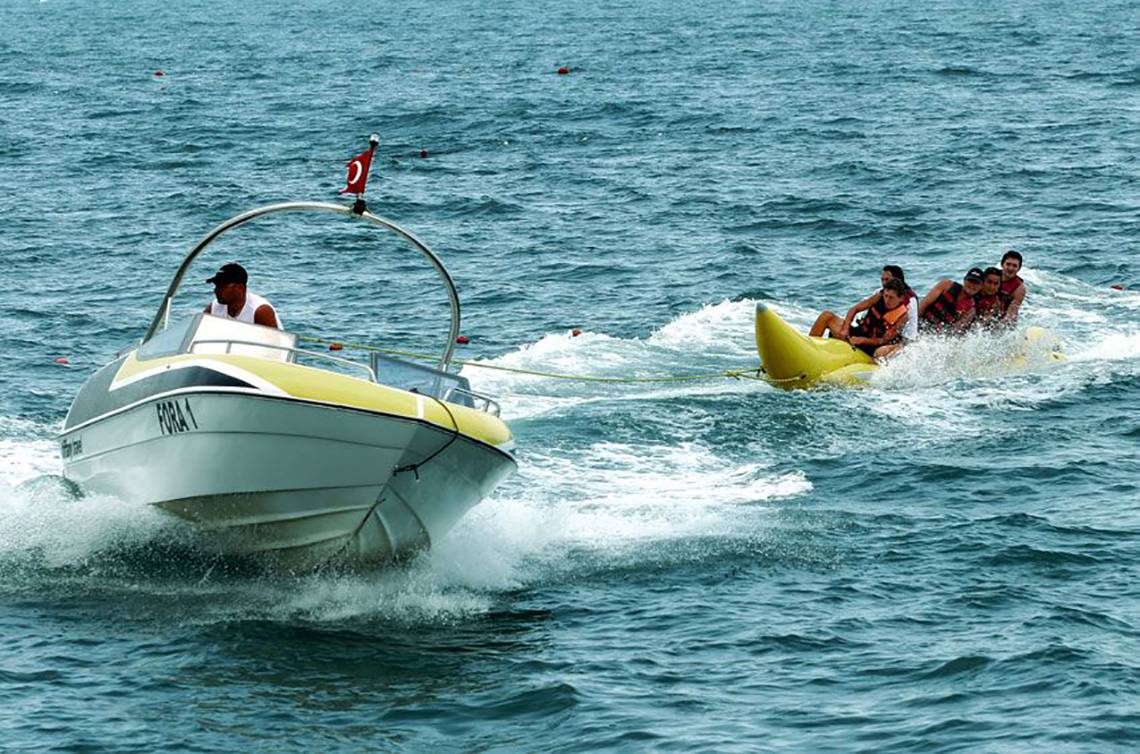 Ein Boot zieht ein Banana Boat mit mehreren Personen im Meer.