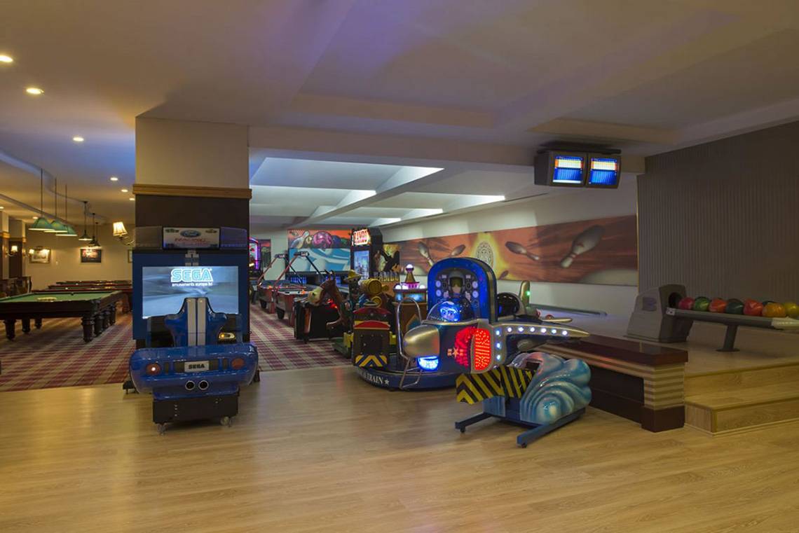 Innenansicht der Spielhalle im Delphin Palace Hotel mit verschiedenen Arcade-Spielen und Billardtischen.