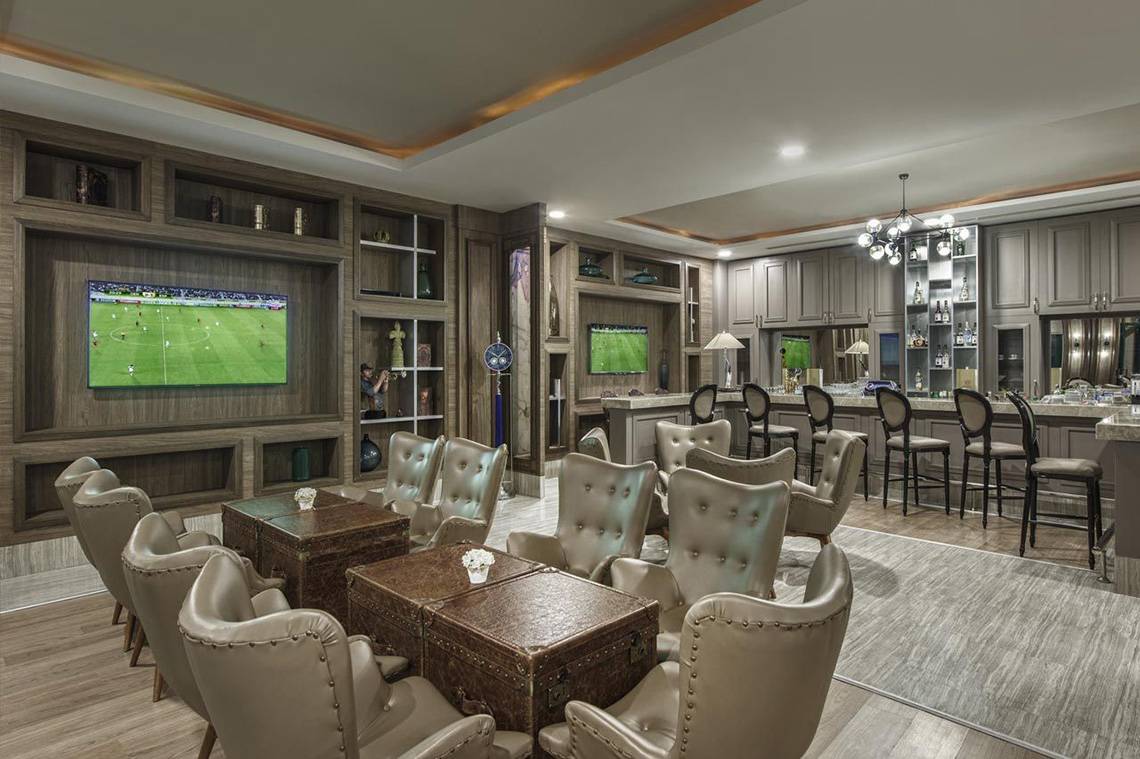 Innenansicht der Sportbar im Delphin Palace Hotel mit Fernsehern, Lederstühlen und Barbereich.