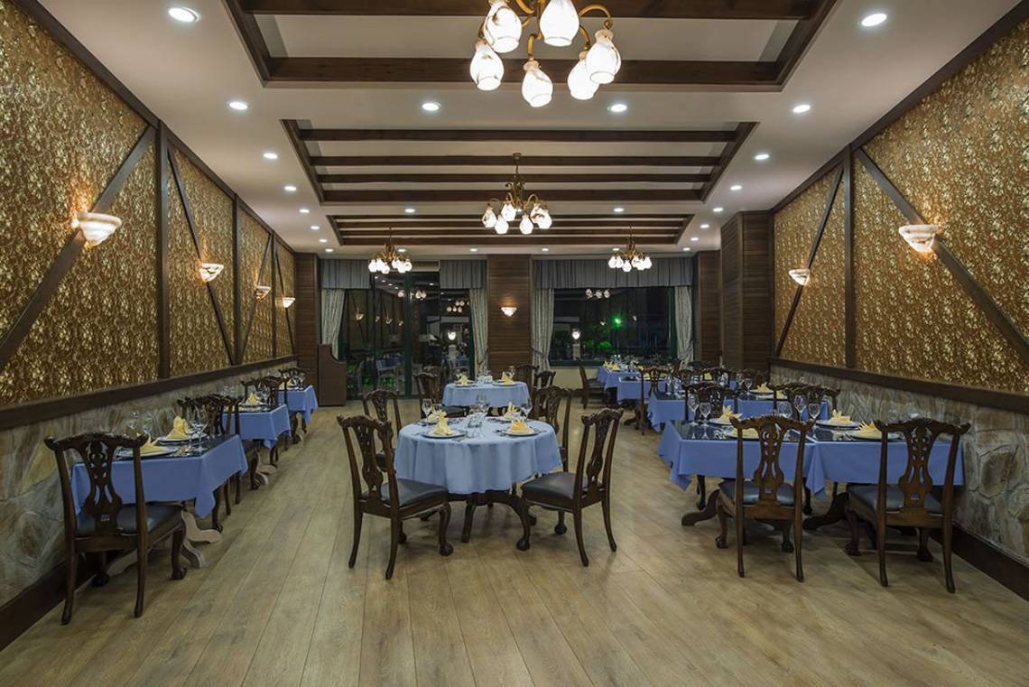 Innenansicht des Restaurants Delphin Palace mit blauen Tischen und Holzböden.