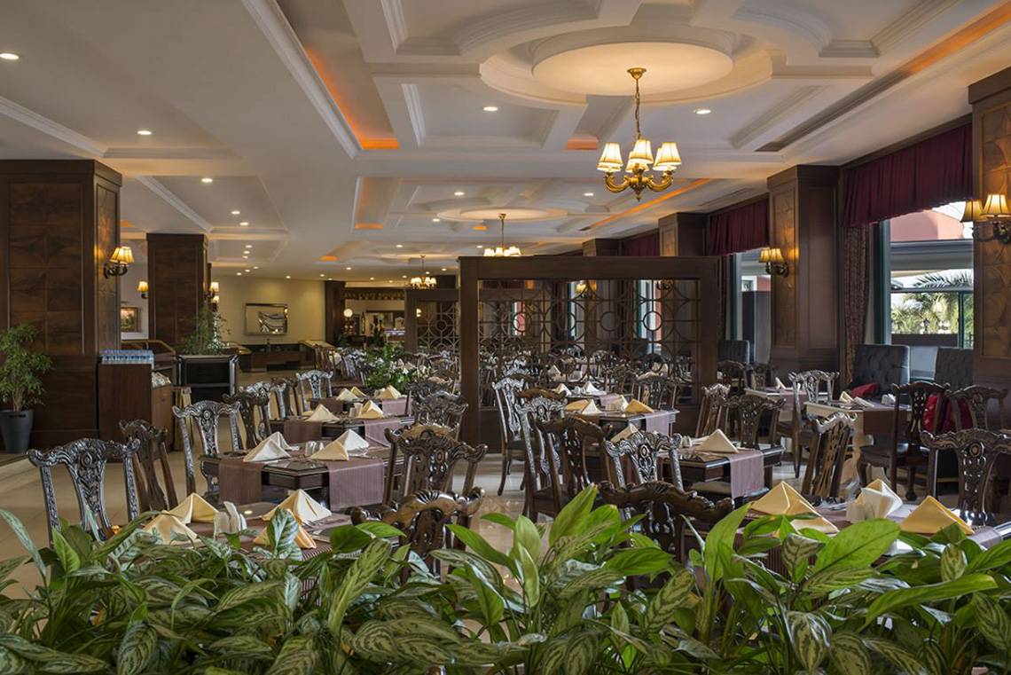 Innenansicht des Restaurants im Delphin Palace Hotel mit gedeckten Tischen und Stühlen.
