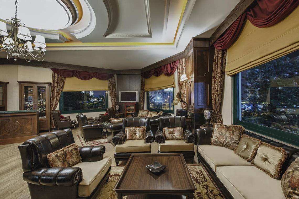 Loungebereich im Delphin Palace Hotel mit Ledersofas, Teppich und großem Fenster.