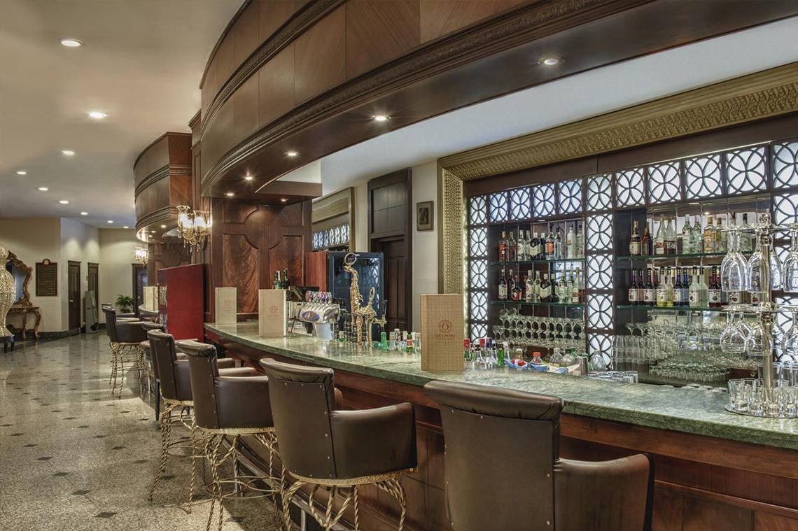 Die Bar des Delphin Palace Hotels mit einer Theke, Stühlen und einer gut bestückten Bar.