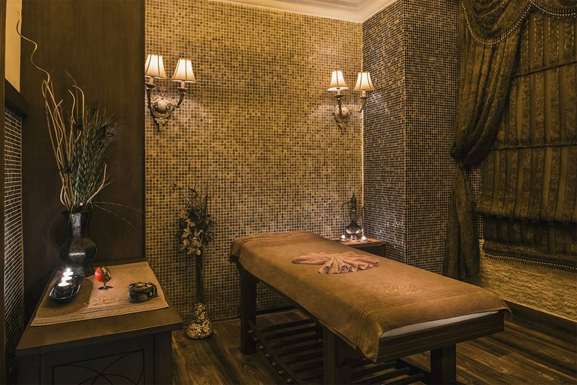 Massageraum im Delphin Palace Hotel mit gemusterten Wänden und einem Massagetisch.