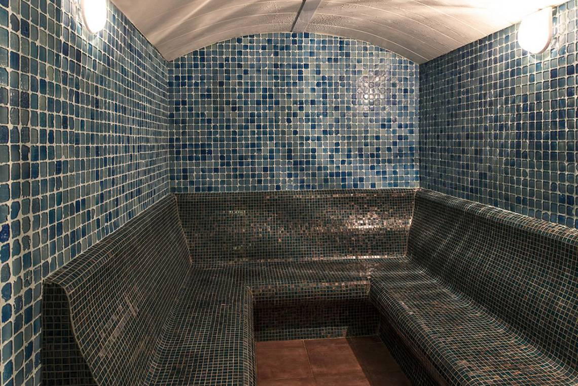 Innenraum der Sauna im Delphin Palace Hotel mit blauen Fliesen und zwei Bänken.