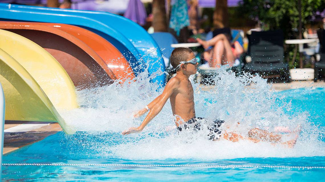 Ein Junge schwimmt im Wasser einer Poolrutsche im Siam Elegance Hotels & Spa.