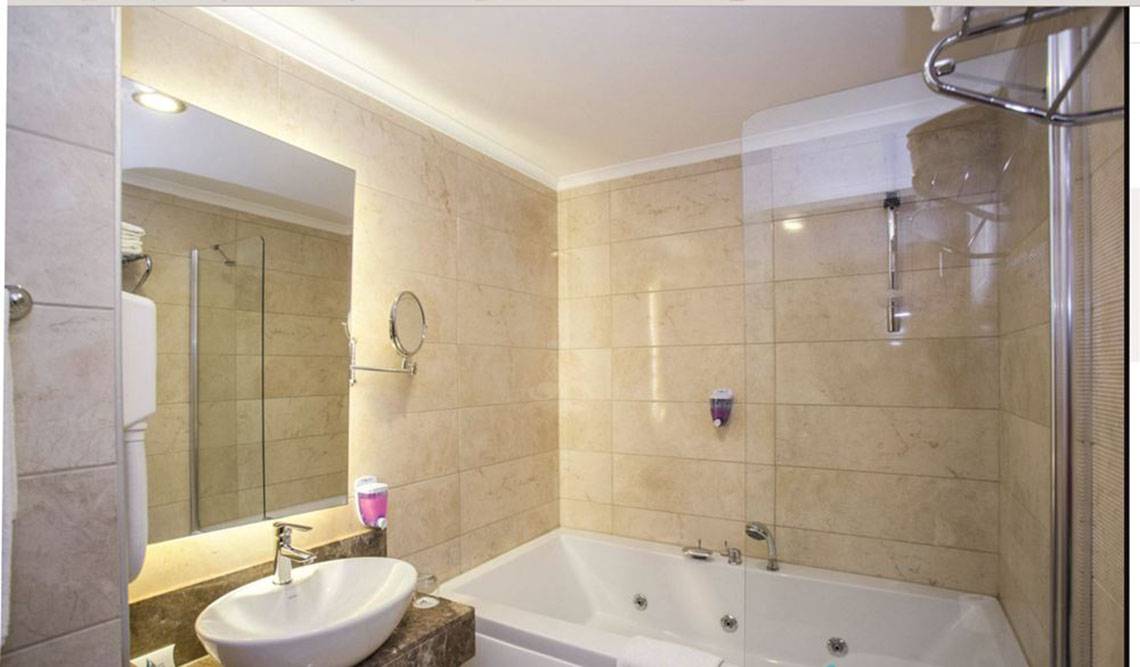 Ein Badezimmer im Side Alegria Hotel & Spa mit einer Badewanne, einem Waschbecken und einem Spiegel.