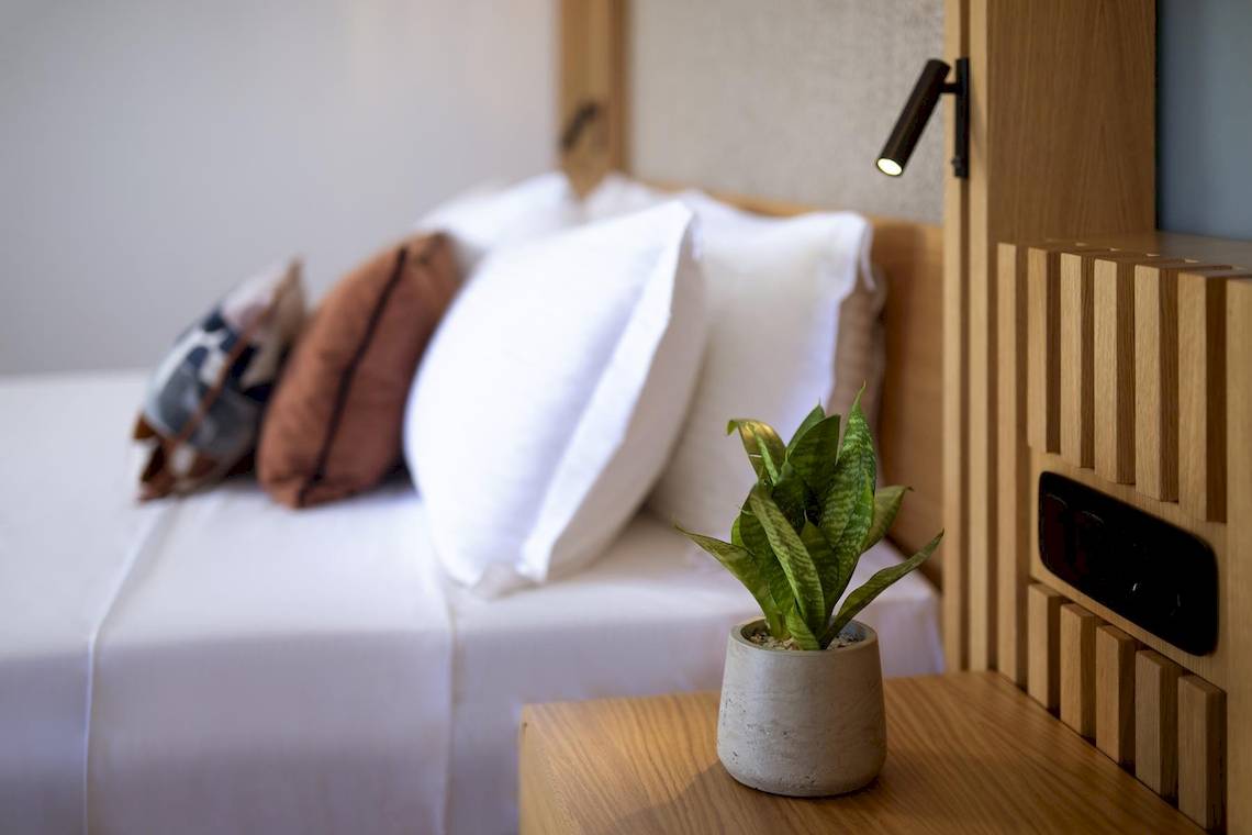 Bett mit Pflanze im Lyttos Mare Hotel, Bettwäsche und Kissen sind weiß
