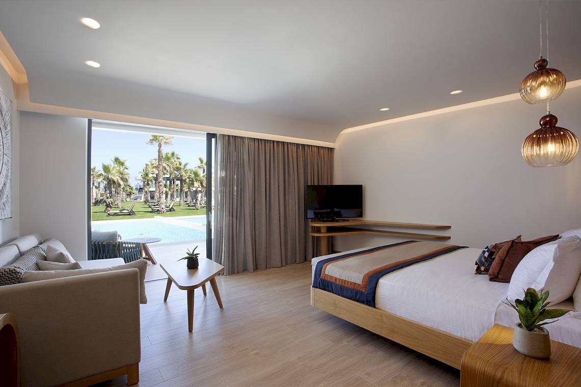 Hotelzimmer von Lyttos Mare mit einem Bett, einer Couch und einem Fernseher.
