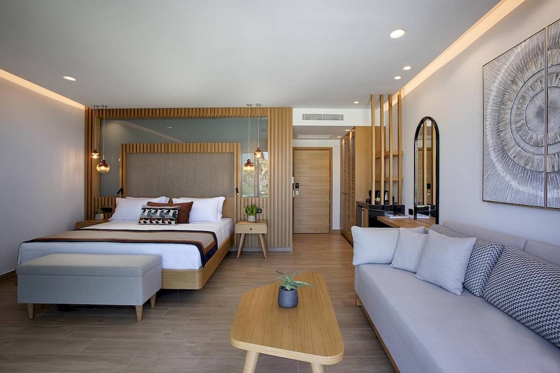 Innenansicht des Schlafzimmers im Lyttos Mare Hotel mit Doppelbett, Sofa, Tisch und Dekor.