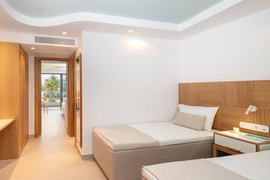Innenansicht eines Zimmers im Lyttos Mare Hotel mit zwei Betten und modernem Interieur.