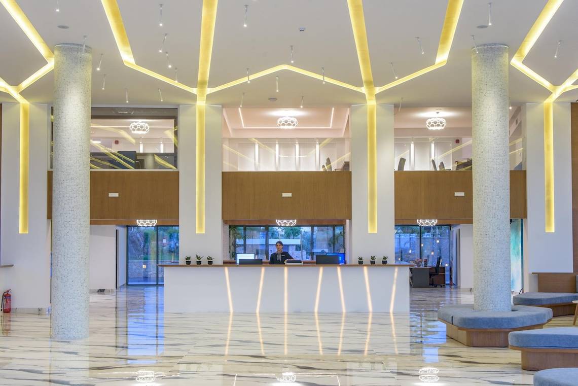 Empfangsbereich des Lyttos Mare Hotels mit Rezeptionist und modernen Möbeln.