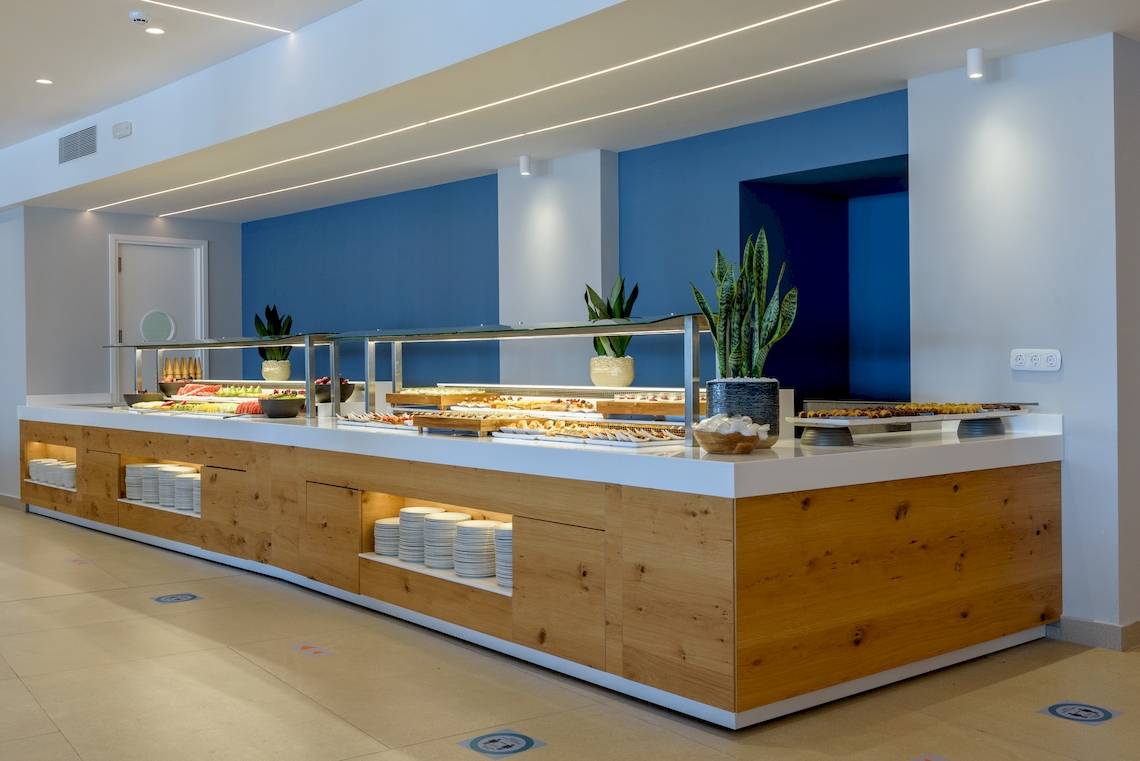 Buffet-Tisch im Lyttos Mare Hotel mit verschiedenen Gerichten und Pflanzen in der Nähe.