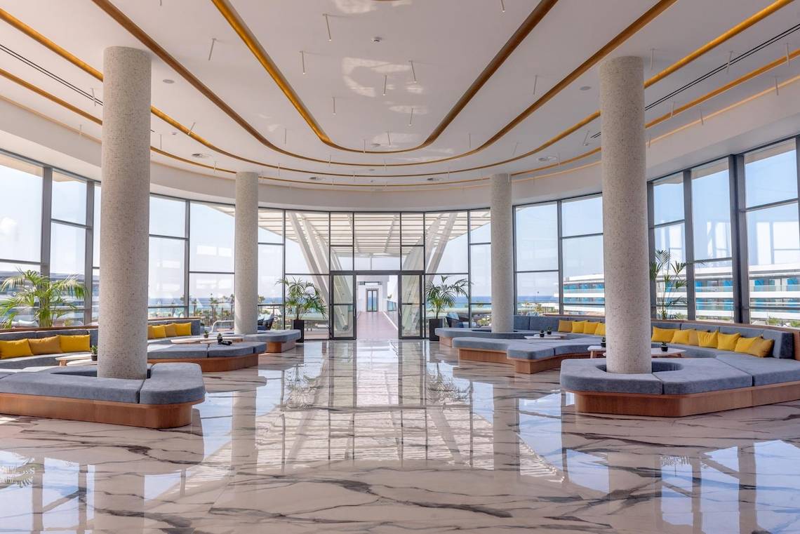 Lobby des Lyttos Mare Hotels mit Marmorboden und großen Fenstern zum Meer.