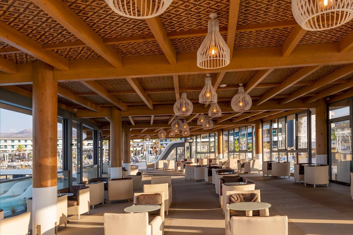 Lounge-Bereich des Lyttos Mare Hotels mit Holzmöbeln und hängenden Lampen.