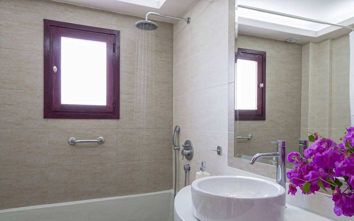 Badezimmer im Veggera Hotel mit Badewanne, Dusche, Waschbecken und Spiegel.