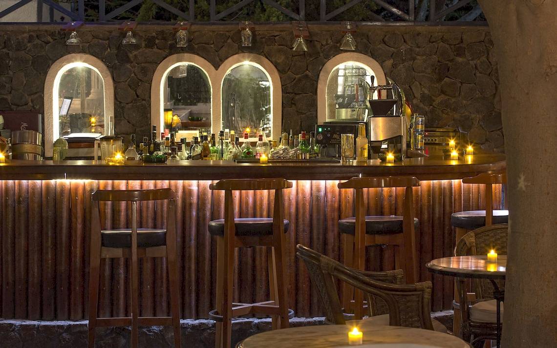 Innenansicht der Bar im Veggera Hotel mit Holzbar, Stühlen, Tischen und brennenden Kerzen.