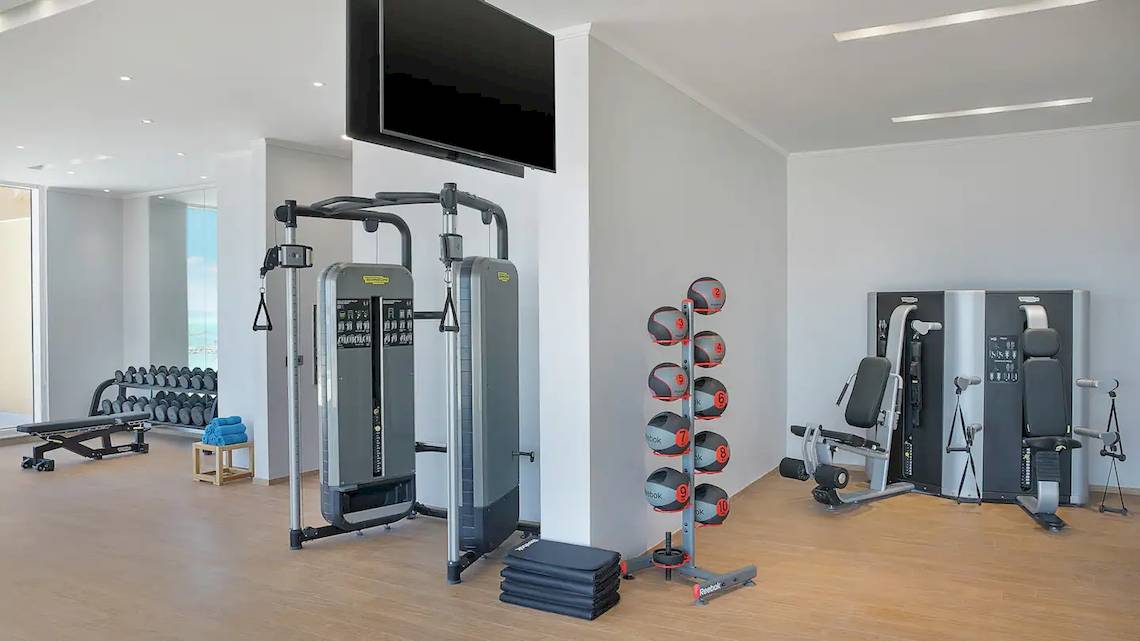 Fitnessbereich im Hilton Hurghada Plaza Hotel mit modernen Trainingsgeräten und Blick auf den Außenbereich.