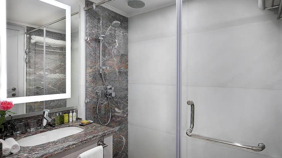 Badezimmer im Hilton Hurghada Plaza Hotel mit Marmorboden, Spiegel und Dusche.