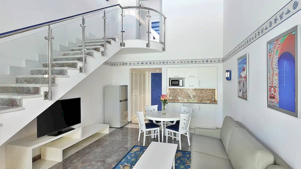 Innenraum des Hilton Hurghada Plaza mit Wohnzimmer, Couch, Tisch, Fernseher und Treppe.
