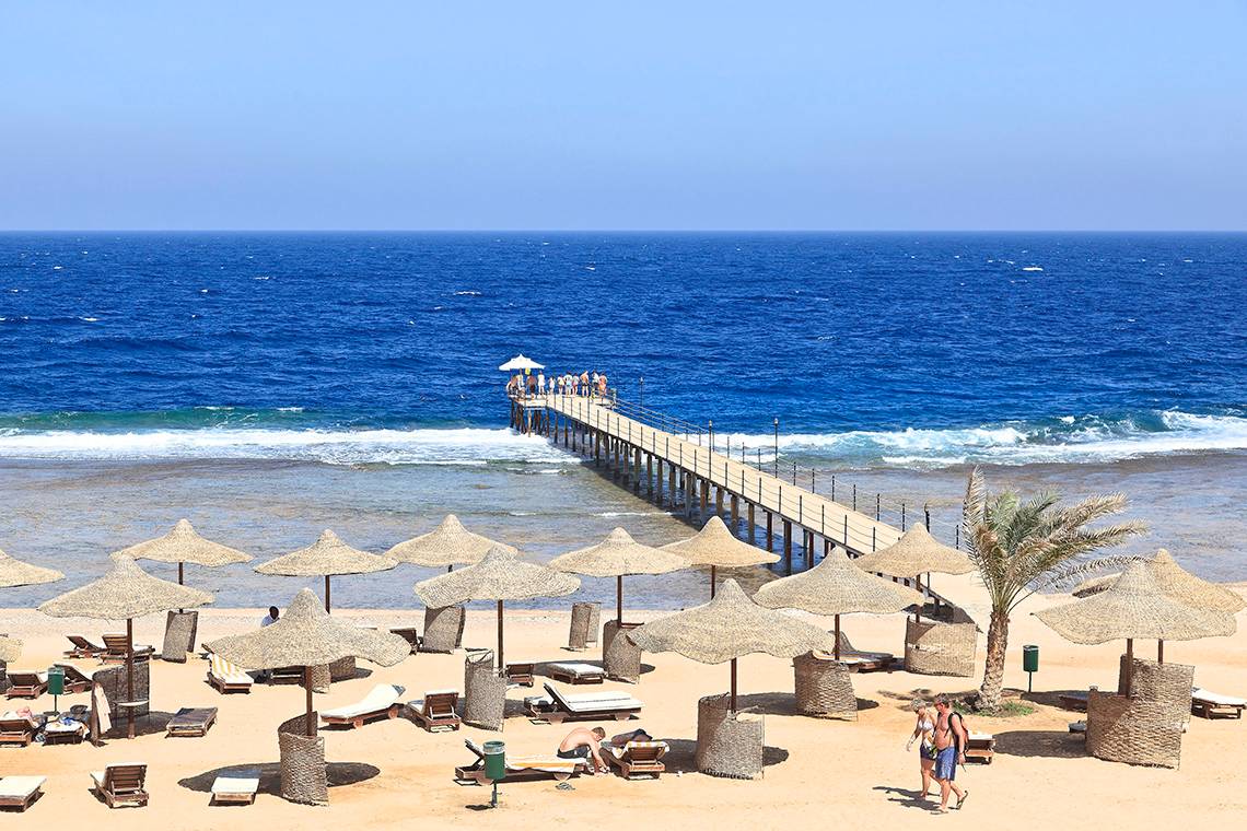 Strand des Three Corners Sea Beach Resorts mit Pier und Sonnenschirmen