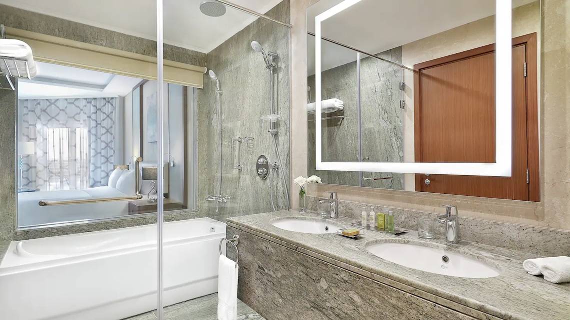 Badezimmer im Hilton Hurghada Plaza mit Badewanne, Dusche und zwei Waschbecken.