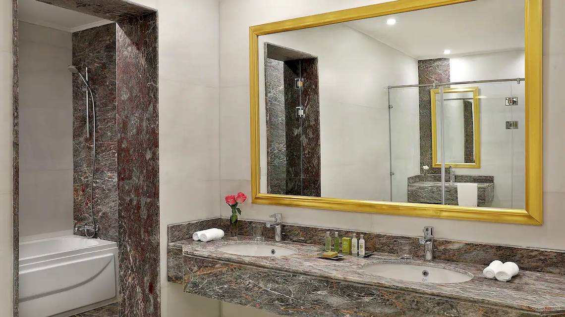 Badezimmer im Hilton Hurghada Plaza mit Badewanne, Waschbecken und Spiegel.