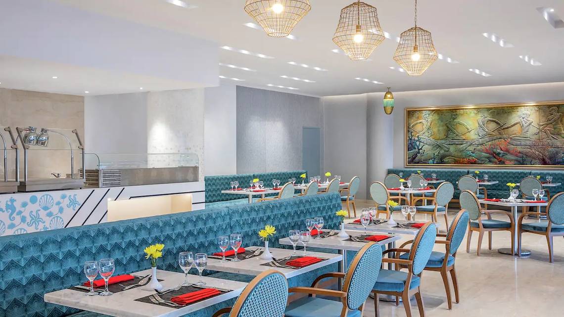 Innenansicht des Restaurants im Hilton Hurghada Plaza mit blauen Möbeln und Gemälden.