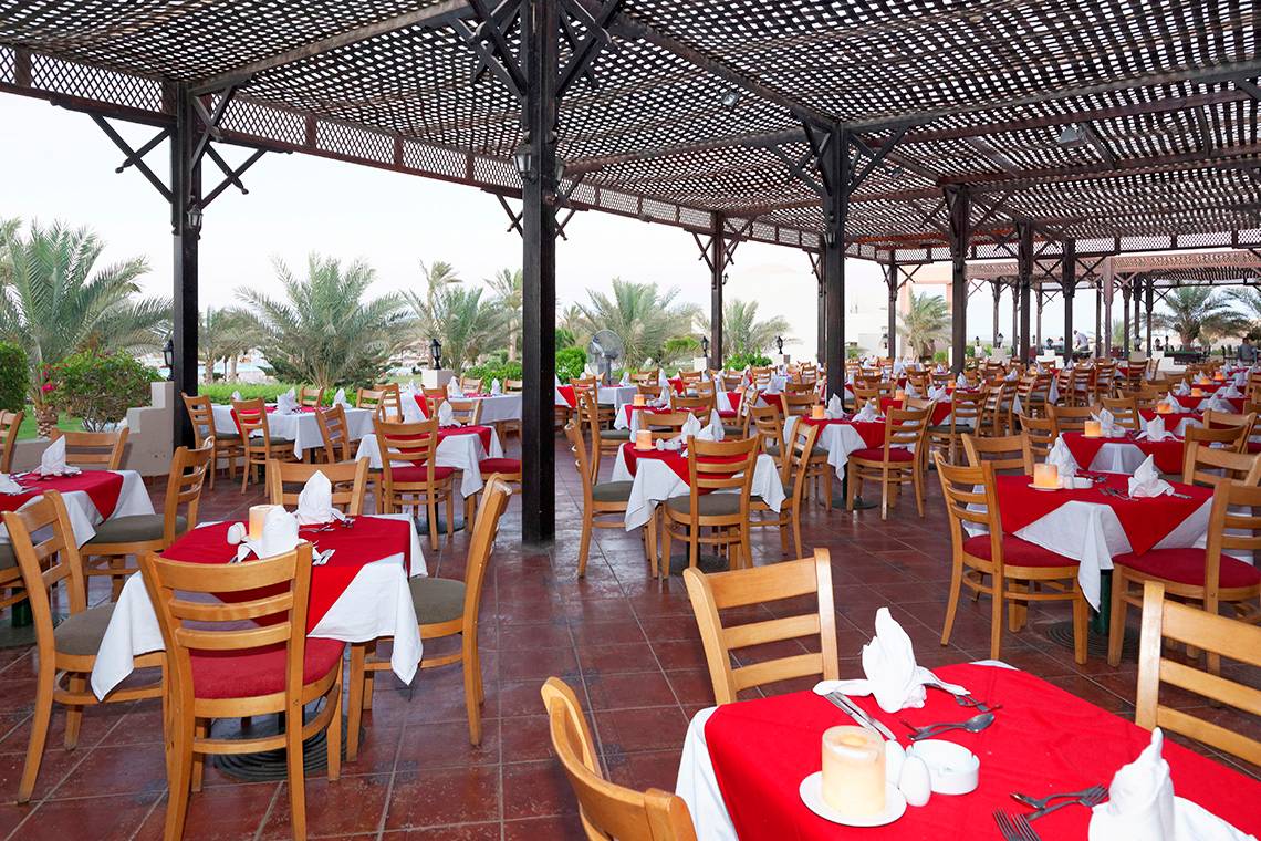 Restaurant im Drei Ecken Meer Strand Resort mit vielen Tischen und Stühlen, teilweise mit roten Tischdecken.