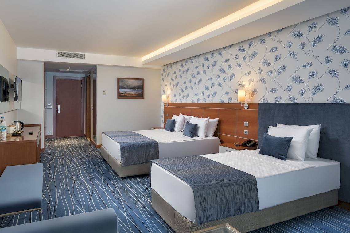 Doppelzimmer im Duja Bodrum Hotel mit zwei Betten, Dekor und Fernseher an der Wand.