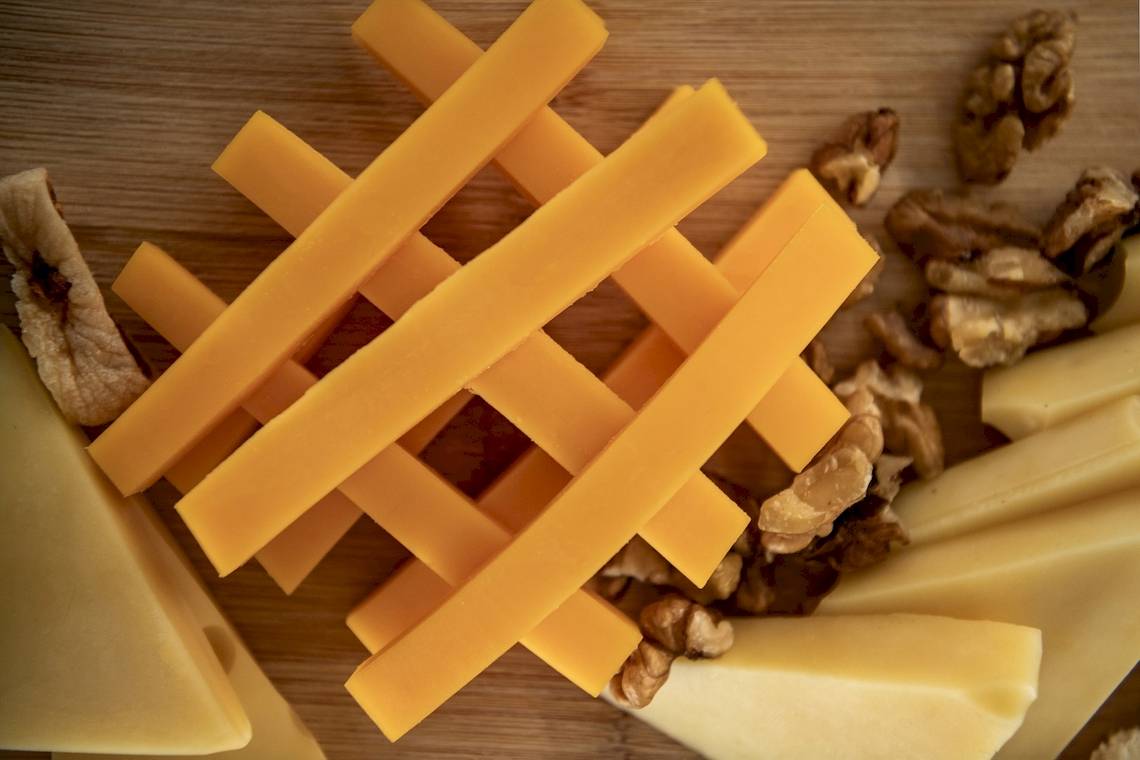 Nahaufnahme von Käsestücken und Nüssen auf einem Holzbrett.