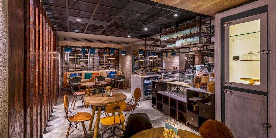Innenansicht des Cafes im Intercontinental Muscat mit Tischen, Stühlen und Holzelementen.