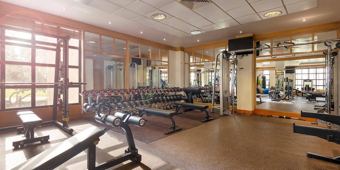 Fitnessstudio im InterContinental Muscat mit vielen Geräten und großen Fenstern.