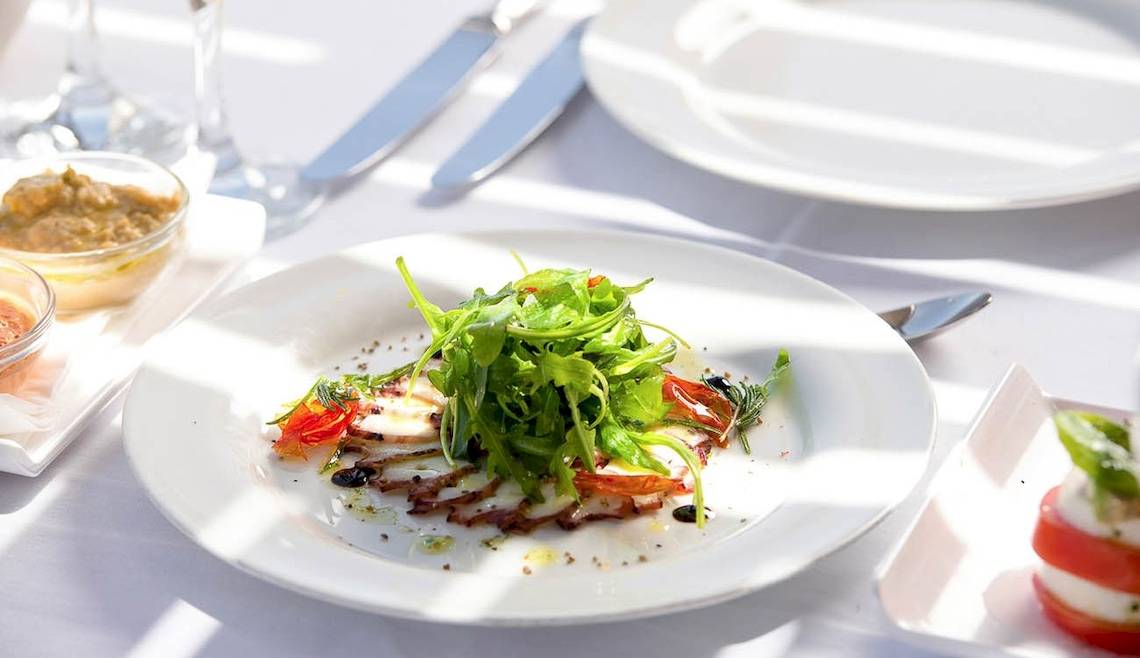 Gedeckter Tisch im Kernos Beach Hotel & Bungalows mit einem Teller Salat und Beilagen.