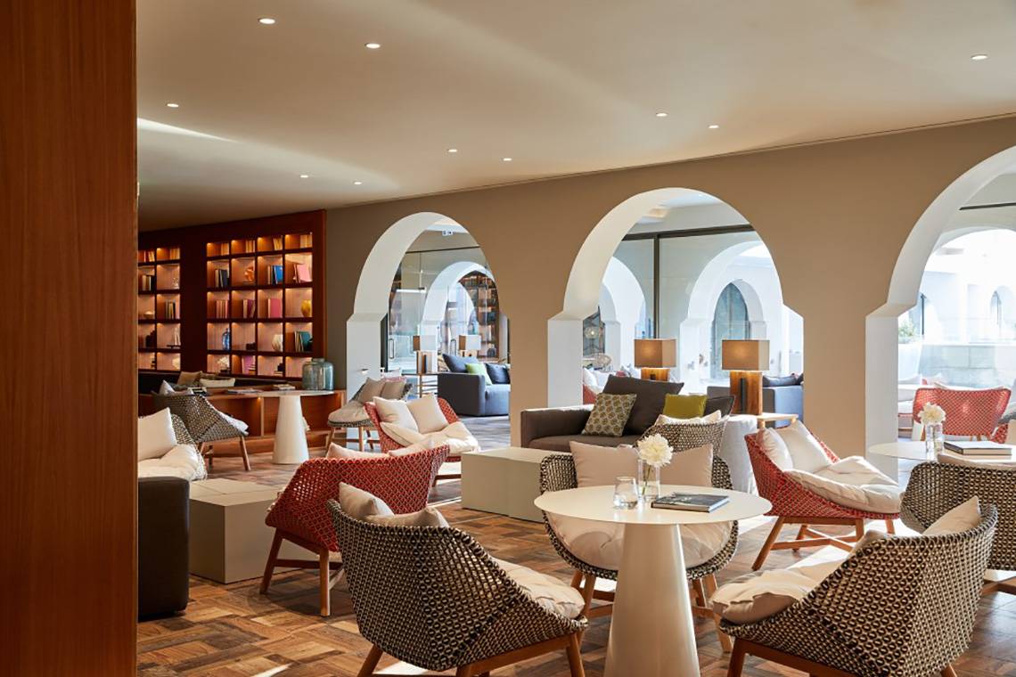 Loungebereich im MarBella Corfu Hotel mit Möbeln und Bücherregalen.