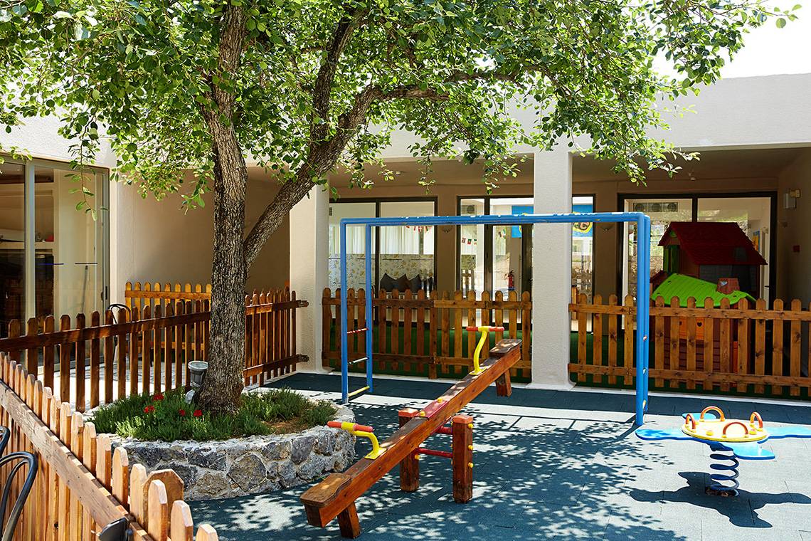 Spielplatz im Freien des MarBella Corfu Hotels mit Schaukeln und Spielhaus.