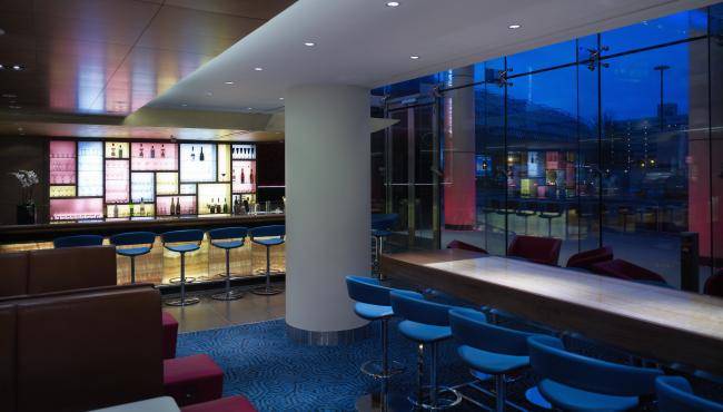 Innenansicht der Bar im Park Plaza County Hall London Hotel mit blauen Stühlen und einem langen Tisch.