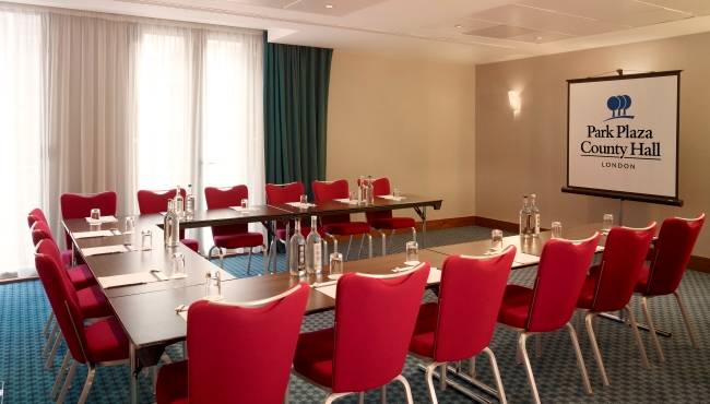 Konferenzraum im Park Plaza County Hall London mit roten Stühlen und Tischen.