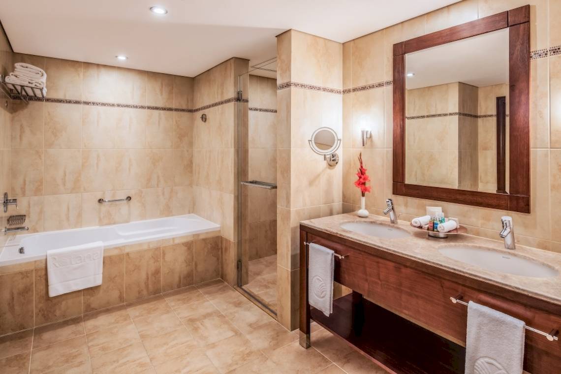 Badezimmer im Khalidiya Palace Rayhaan by Rotana mit Badewanne, Dusche, Spiegel und Waschbecken.