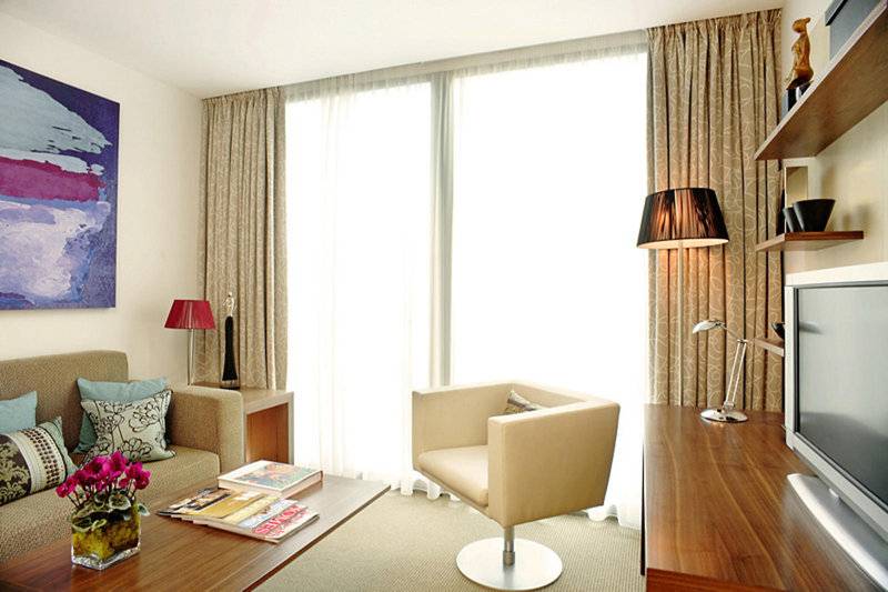 Wohnzimmer im Park Plaza County Hall London Hotel mit Sofa, Stuhl, Tisch und Fernseher.