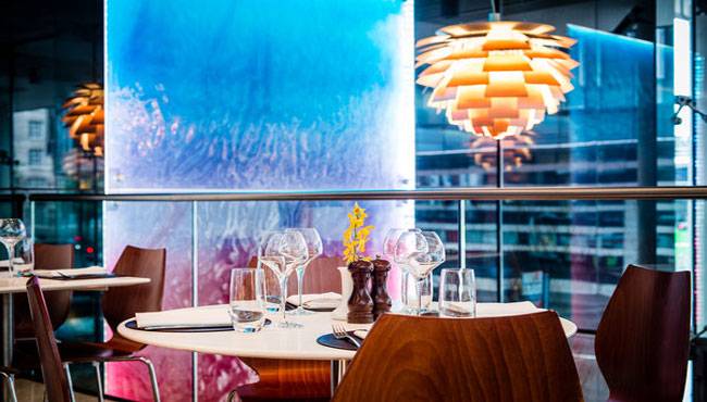 Innenansicht des Restaurants im Park Plaza County Hall London mit Tisch, Gläsern und blauer Wand