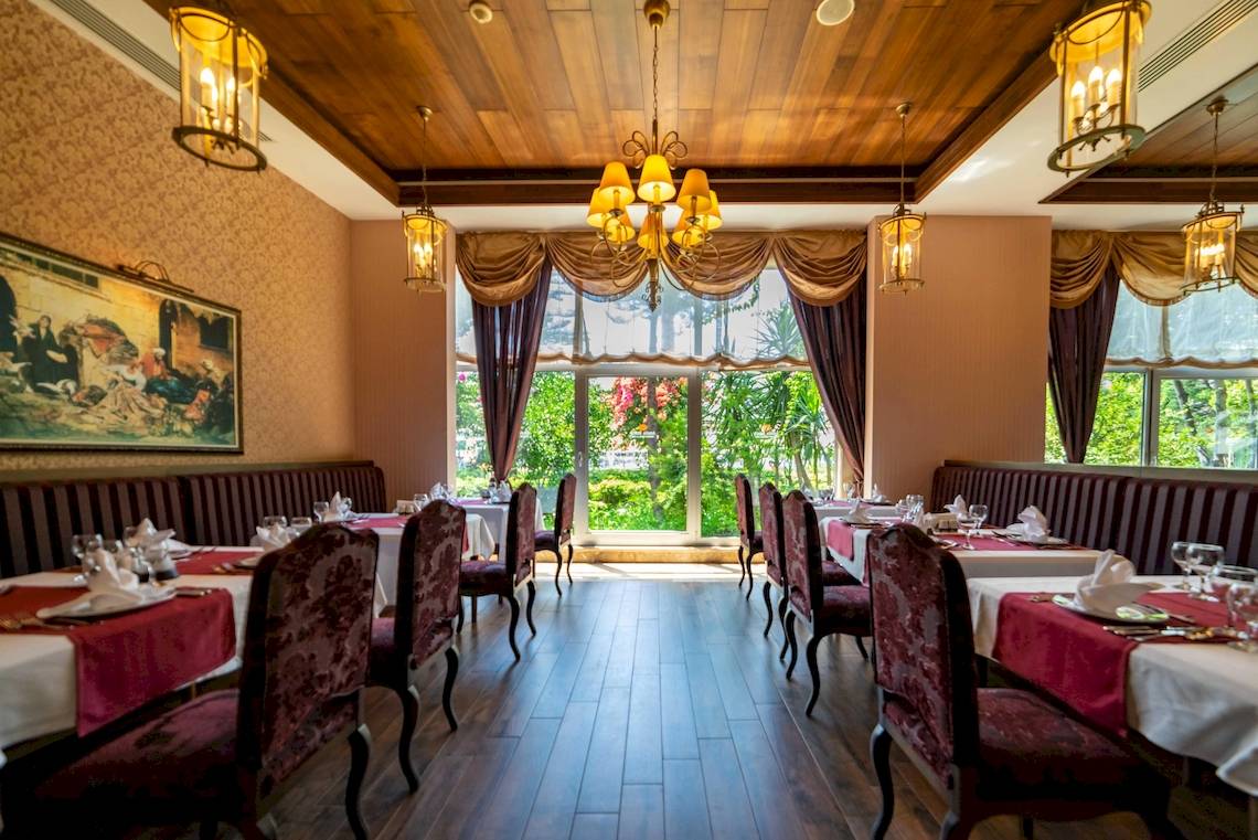 Innenansicht des Restaurants im Vita Silva Hotel mit gepolsterten Bänken, gedeckten Tischen und großen Fenstern.