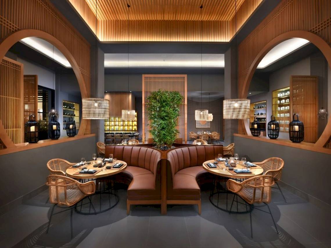 Das Interieur des Hotels 'Steigenberger Resort Ras Soma' zeigt ein Restaurant mit braunen Ledersofas, runden Tischen, hängenden Lampen und einer zentralen Pflanze.